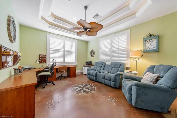 Office with ceiling fan, a raised ceiling, and ornamental molding