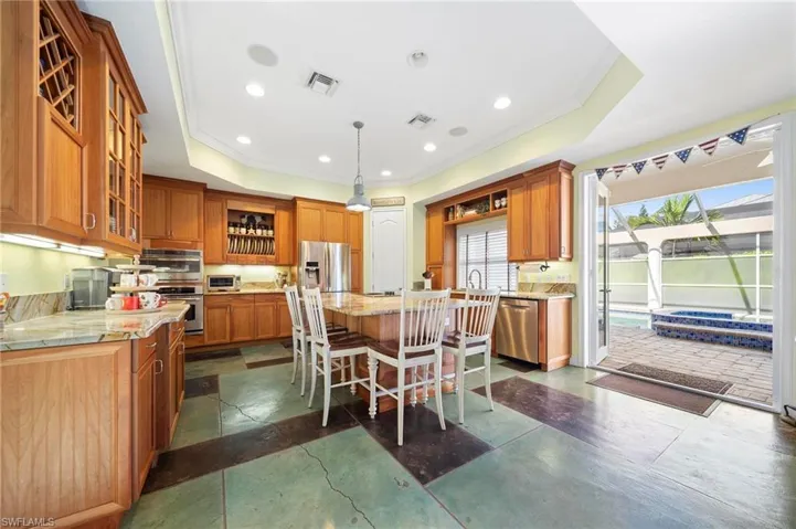 Kitchen featuring a raised ceiling, pendant lighting, a breakfast bar, a kitchen island, and appliances with stainless steel finishes