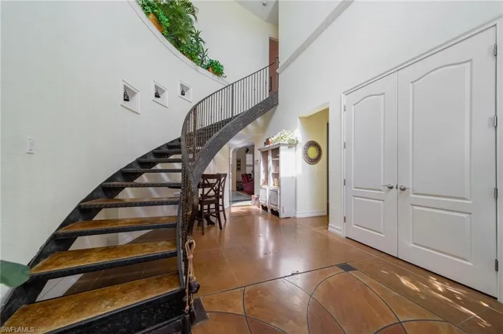 Stairway with tile patterned floors and a high ceiling