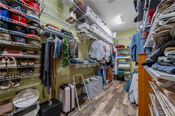 Walk in closet with hardwood / wood-style floors
