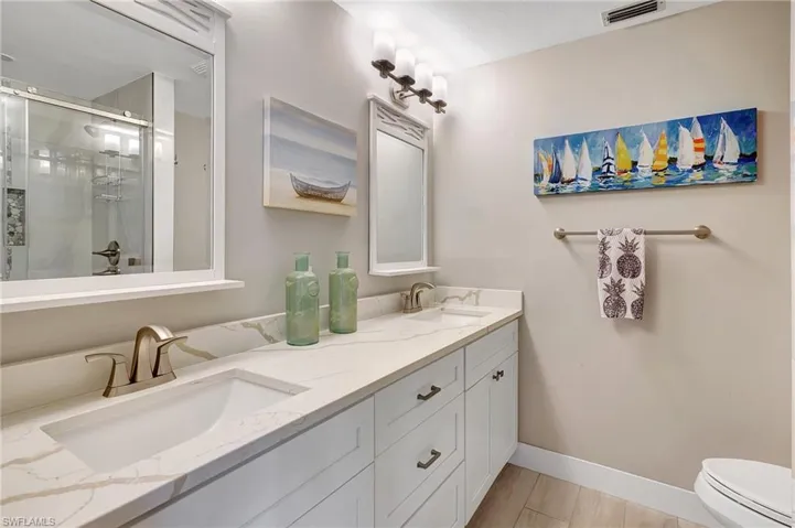 Bathroom featuring toilet, vanity, and walk in shower