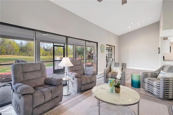 Living room featuring ceiling fan and high vaulted ceiling