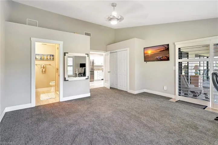 Unfurnished bedroom featuring multiple windows, carpet floors, lofted ceiling, and ensuite bath