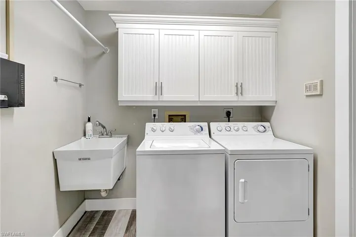 Laundry room with cabinets, independent washer and dryer, and sink