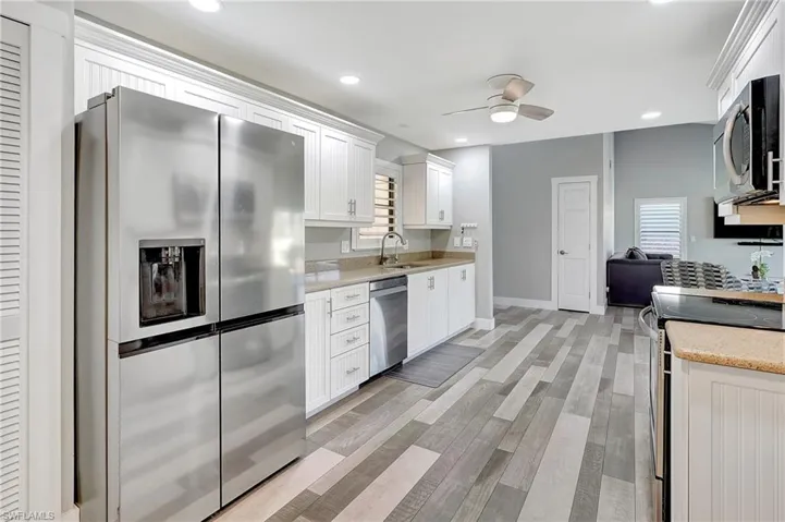 Kitchen with light stone countertops, sink, white cabinetry, and stainless steel appliances