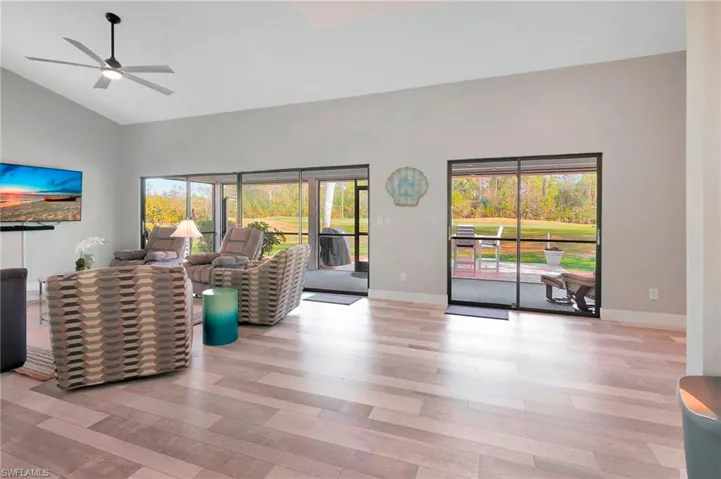 Living room with ceiling fan, light wood-type flooring, and high vaulted ceiling