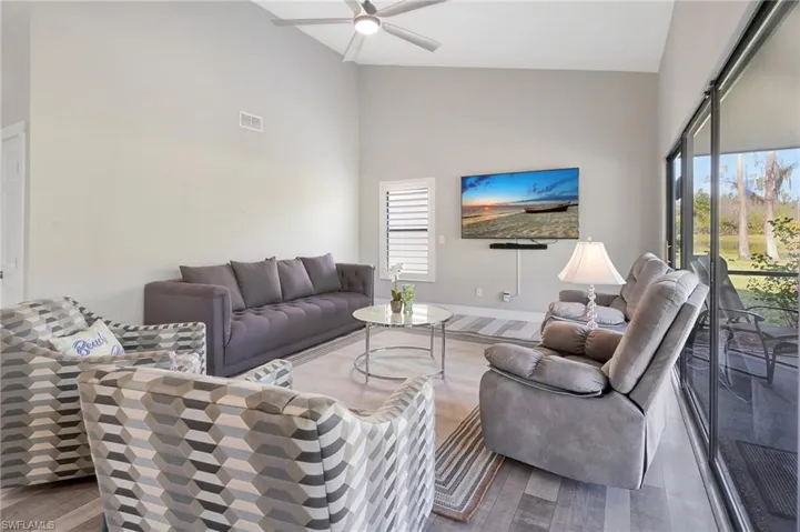 Living room featuring dark hardwood / wood-style floors, ceiling fan, and high vaulted ceiling