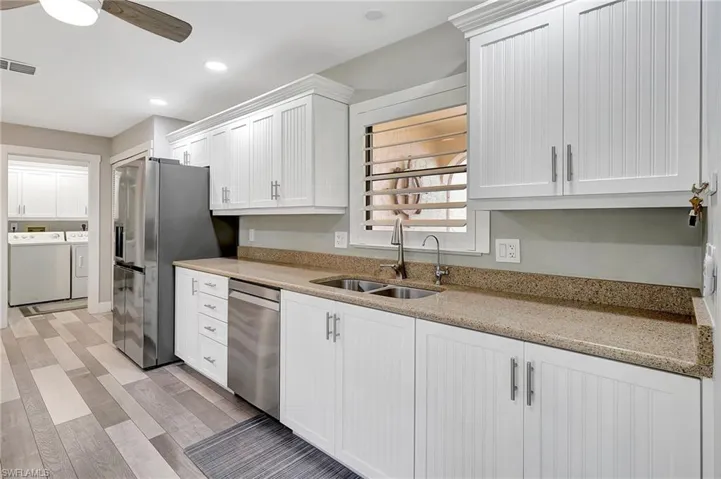 Kitchen featuring ceiling fan, sink, stainless steel appliances, independent washer and dryer, and white cabinets