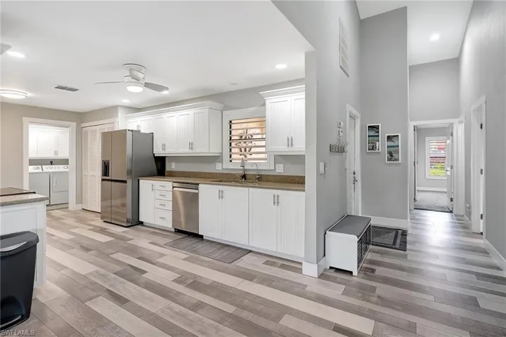 Kitchen with white cabinets, sink, ceiling fan, stainless steel appliances, and washing machine and clothes dryer