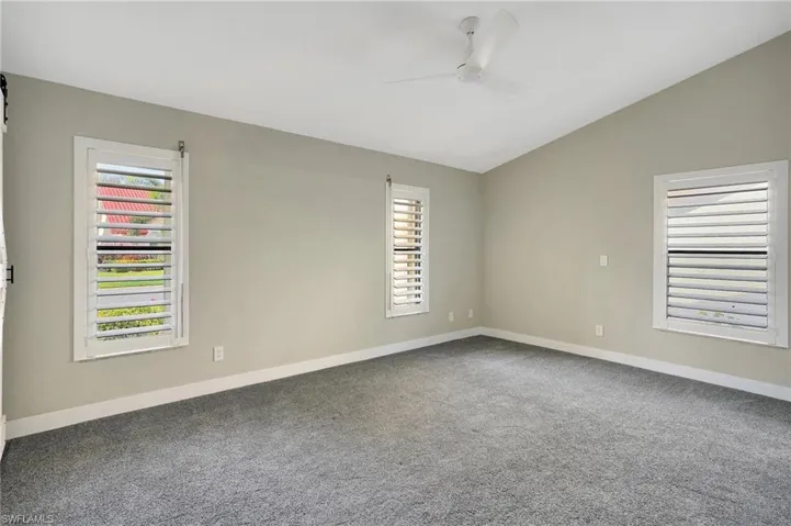 Empty room with carpet flooring, ceiling fan, and lofted ceiling