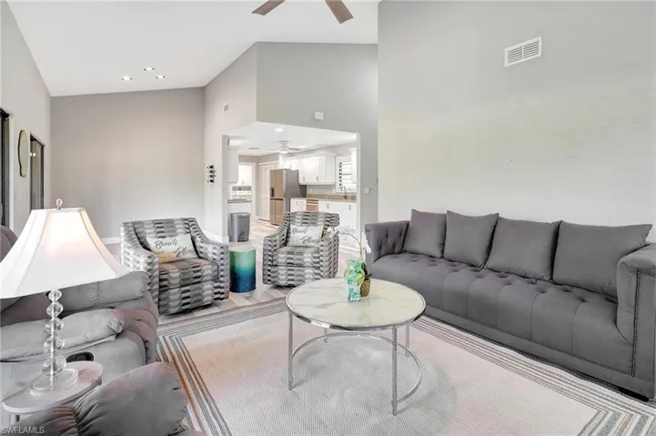 Living room with ceiling fan, sink, and high vaulted ceiling