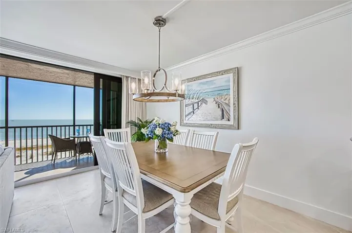 Dining room with crown molding, hanging lights, and a water view