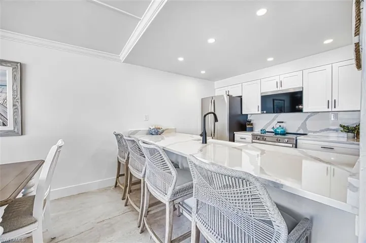 Kitchen featuring a kitchen breakfast bar, white cabinets, quartz counters, and stainless steel appliances