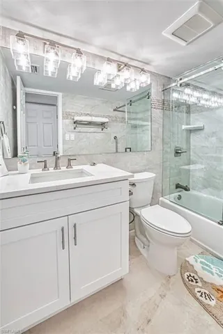 Bathroom featuring tile walls, vanity, and bath / shower combo with glass door