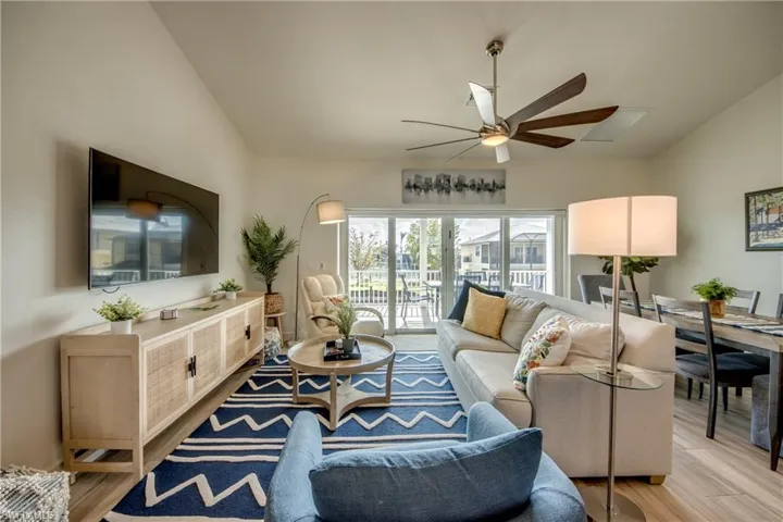 Living room with vaulted ceiling, light hardwood / wood-style floors, and ceiling fan