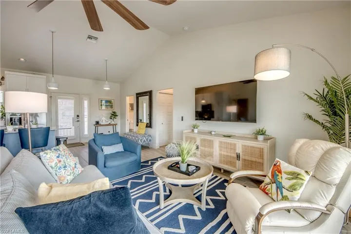 Living room featuring vaulted ceiling, ceiling fan, and light wood-type flooring