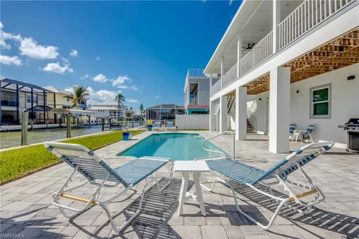 View of pool featuring a water view, ceiling fan, a grill, and a patio area