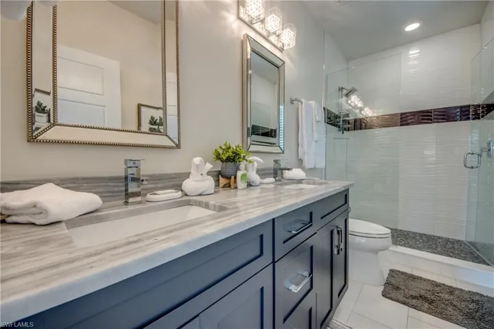 Bathroom featuring walk in shower, vanity, toilet, and tile patterned flooring