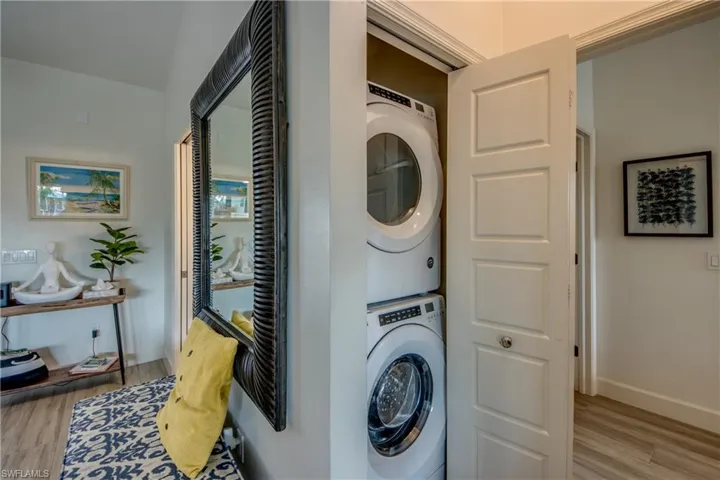 Clothes washing area with stacked washer and dryer and light hardwood / wood-style floors