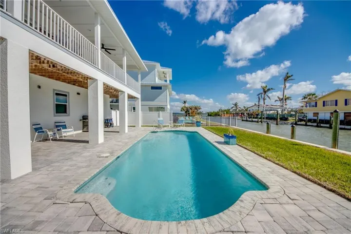 View of pool with grilling area, a patio area, ceiling fan, and a water view
