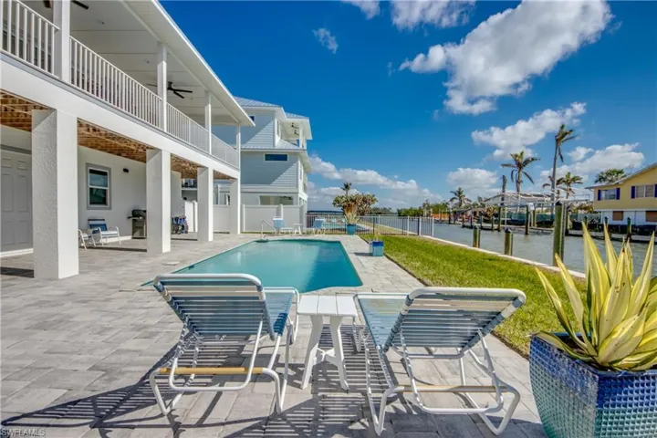 View of swimming pool with a patio, a water view, and ceiling fan