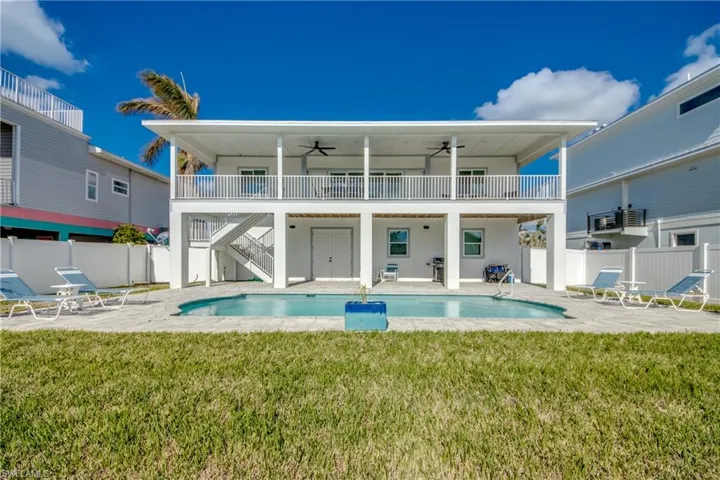 Back of property featuring a fenced in pool, a patio area, ceiling fan, and a lawn