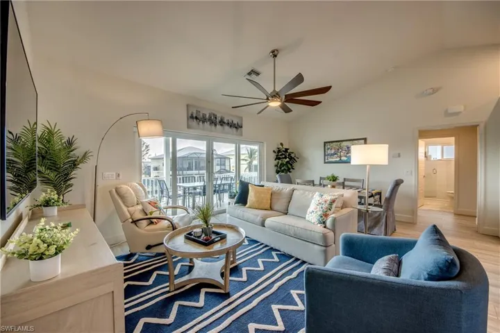 Living room with lofted ceiling, a wealth of natural light, ceiling fan, and light hardwood / wood-style flooring
