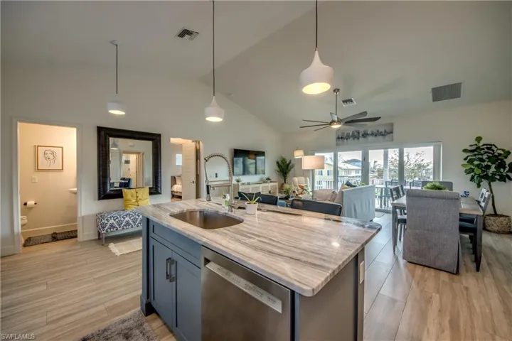Kitchen featuring dishwasher, sink, hanging light fixtures, and light wood-type flooring