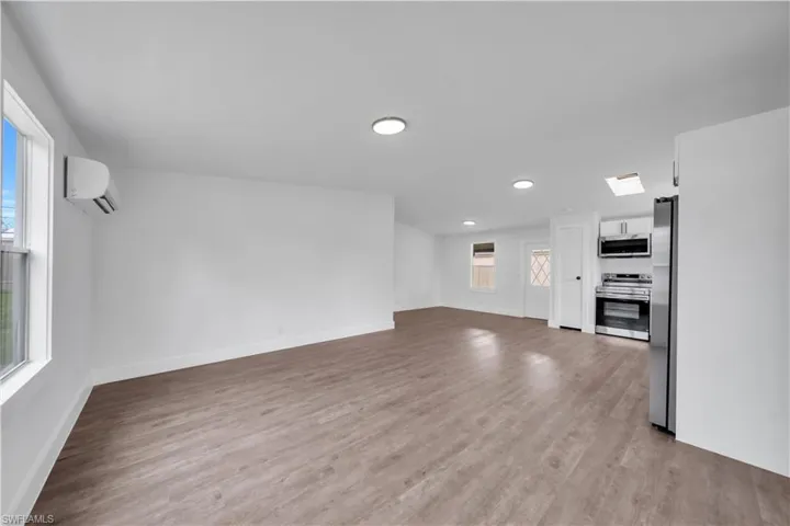 Open-concept living area with wood-finish flooring, recessed lighting, and a ductless mini-split system
