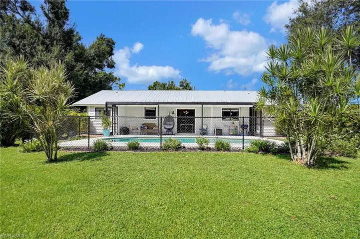 Rear view of house with a fenced in pool and a lawn