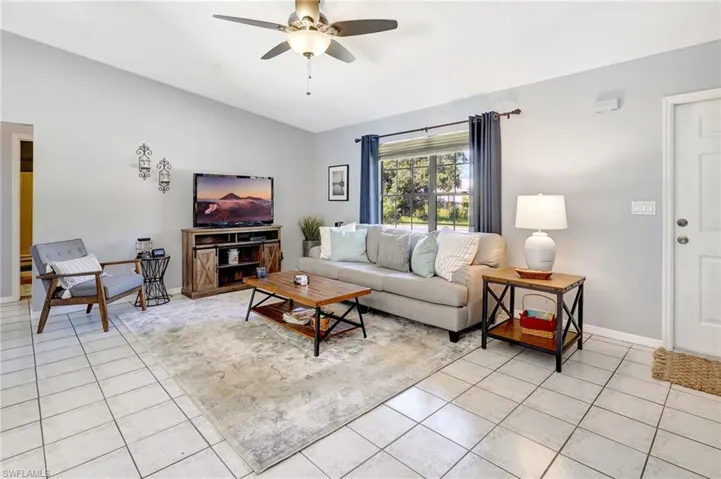 Tiled living room with lofted ceiling and ceiling fan