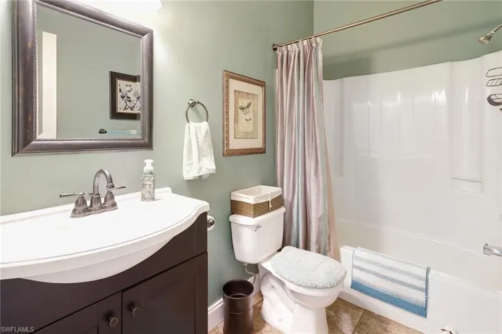 Full bathroom featuring tile patterned flooring, shower / bath combination with curtain, toilet, and vanity