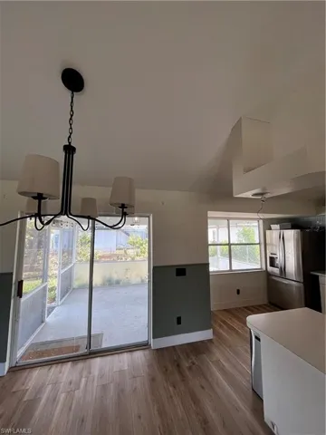 Unfurnished dining area featuring light wood-style floors, a chandelier, and a wainscoted wall