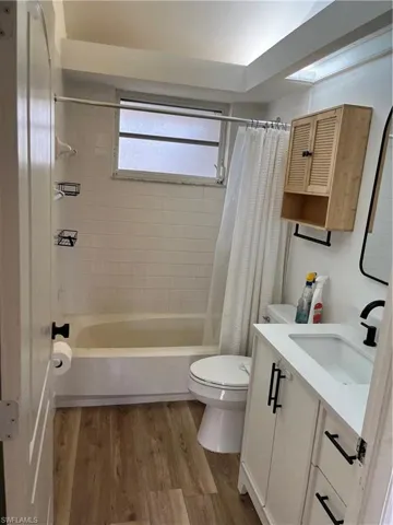 Full bath with vanity, light wood finished floors, and shower / bathtub combination with curtain