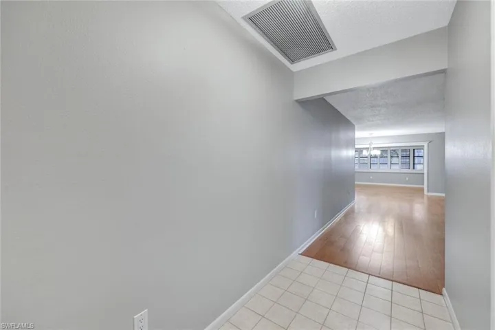 Corridor featuring a textured ceiling, a chandelier, and light tile patterned floors