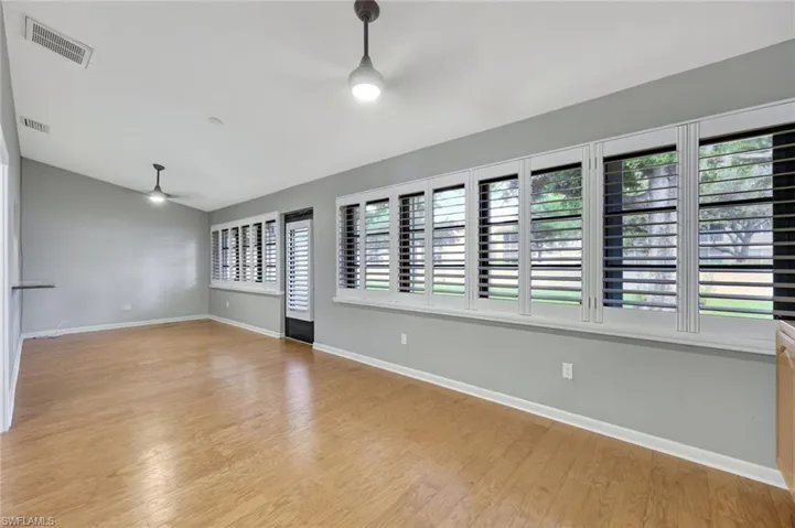 Unfurnished room with ceiling fan, light wood finished floors, and lofted ceiling