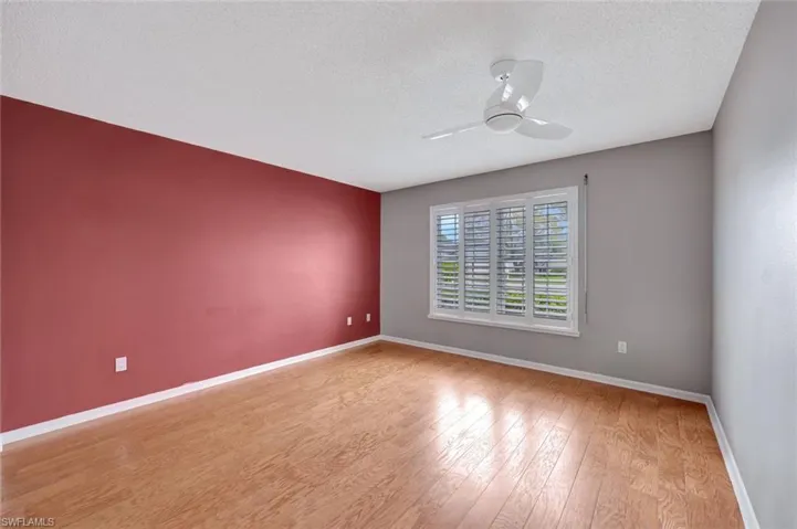 Empty room with wood finished floors, a ceiling fan, and a textured ceiling