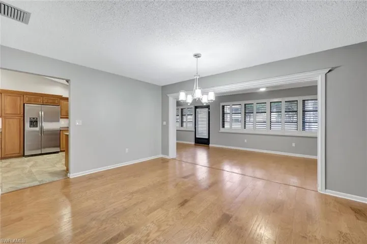 Unfurnished dining area with a chandelier, a textured ceiling, and light wood finished floors