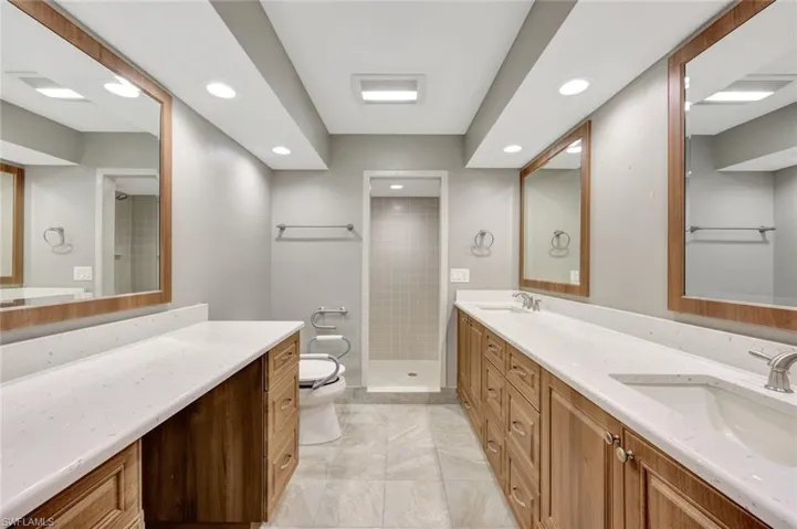 Bathroom featuring recessed lighting, double vanity, a tile shower, and marble finish floors