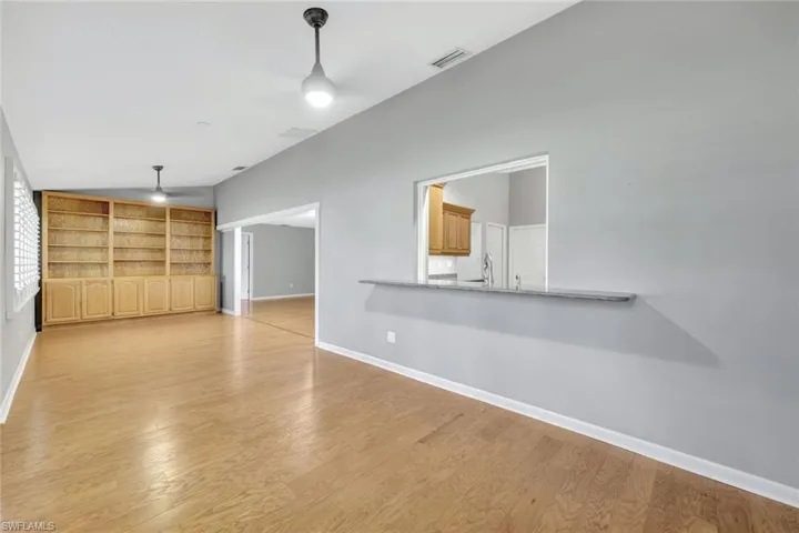 Unfurnished living room featuring light wood finished floors, lofted ceiling, and ceiling fan
