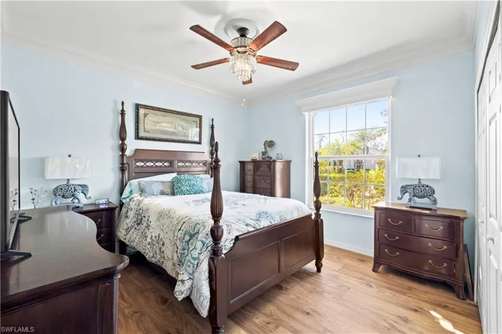 Bedroom with ornamental molding, wood finished floors, a closet, and a ceiling fan