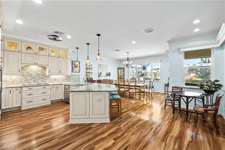 Kitchen with decorative light fixtures, light stone counters, a peninsula, a breakfast bar area, and crown molding