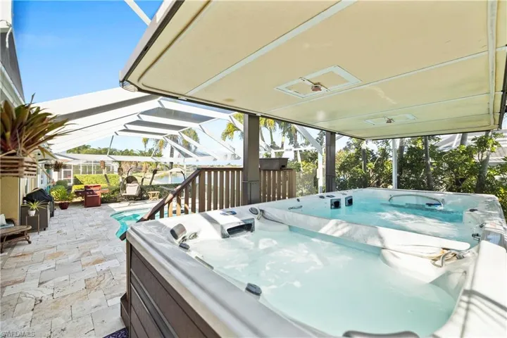 View of patio / terrace with a hot tub, glass enclosure, and a grill
