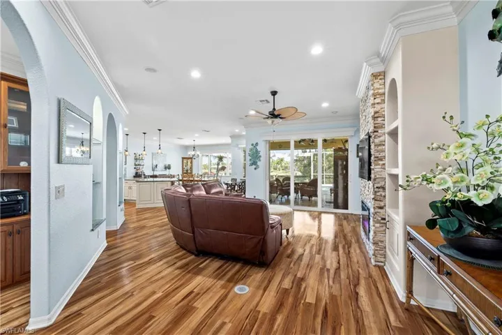 Living room with crown molding, arched walkways, light wood-type flooring, recessed lighting, and ceiling fan