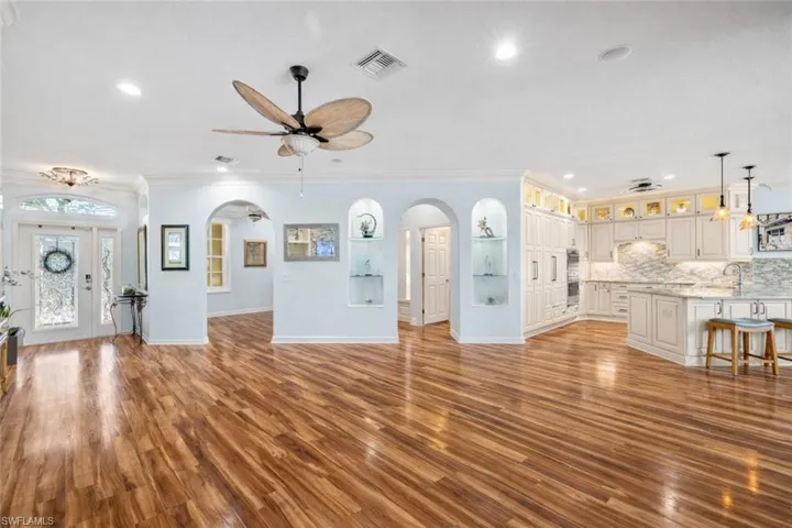Unfurnished living room featuring light wood-style flooring, arched walkways, crown molding, recessed lighting, and ceiling fan