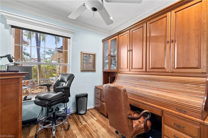Office space with light wood-style flooring, crown molding, and ceiling fan