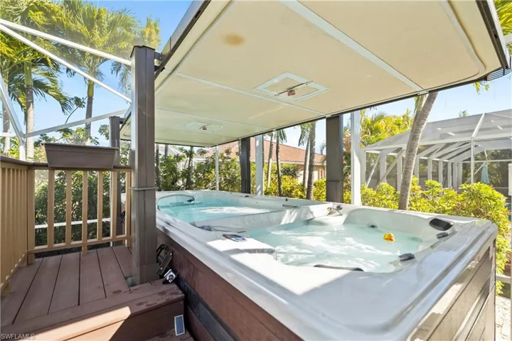 Wooden deck featuring glass enclosure, a hot tub, and a sunroom