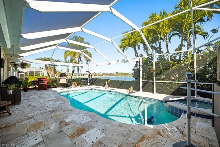 View of swimming pool with a patio, a sunroom, a lanai, a pool with connected hot tub, and a water view