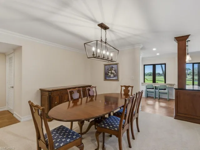 Dining room with crown molding, suspended lighting, and light carpet