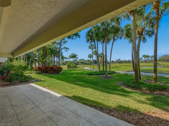 View of grassy yard with a water view, view of golf course, and a patio area